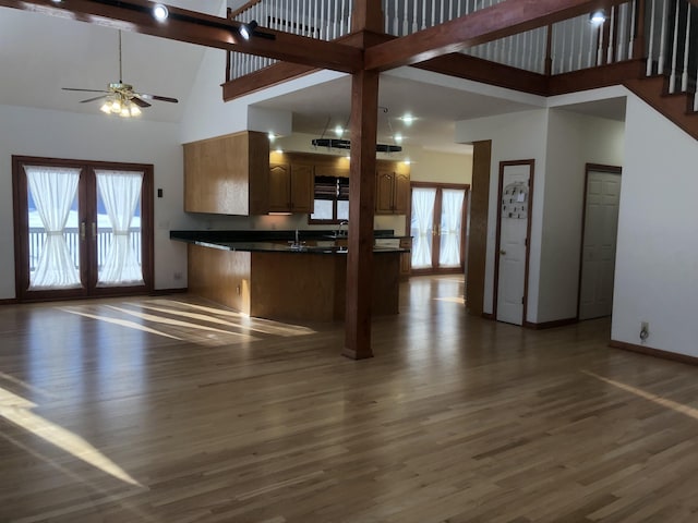 kitchen featuring dark wood-type flooring, french doors, kitchen peninsula, and a high ceiling