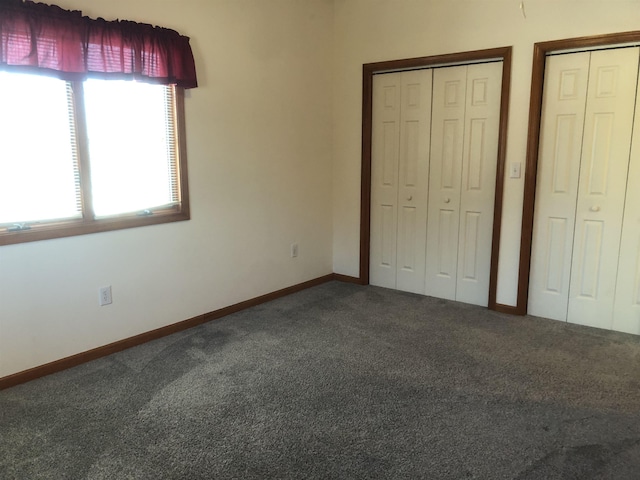 unfurnished bedroom with carpet flooring and two closets