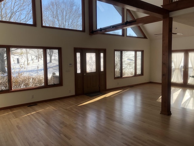 foyer with beam ceiling, wood-type flooring, a healthy amount of sunlight, and high vaulted ceiling