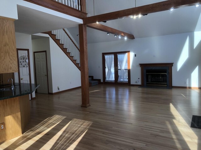 unfurnished living room with french doors, sink, dark hardwood / wood-style flooring, beamed ceiling, and a high ceiling