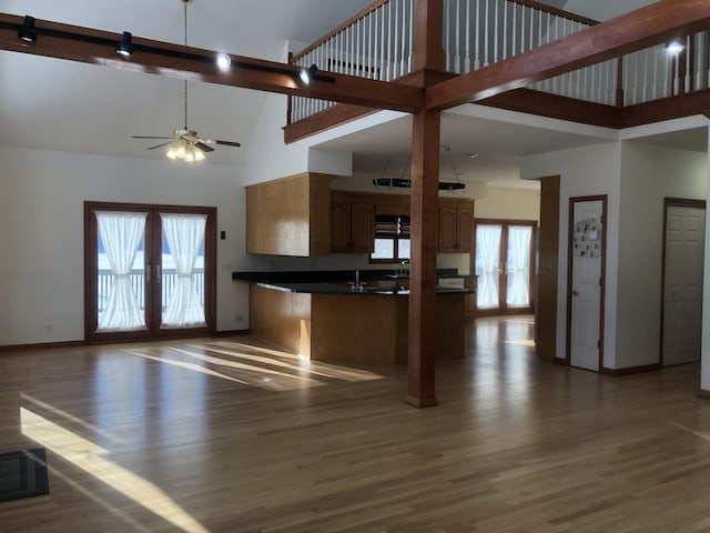 kitchen with french doors, ceiling fan, dark hardwood / wood-style flooring, kitchen peninsula, and a towering ceiling