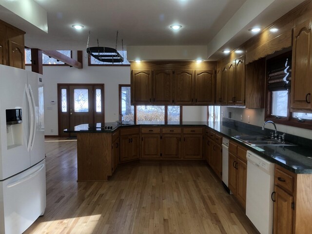 kitchen with hardwood / wood-style flooring, sink, white appliances, and kitchen peninsula