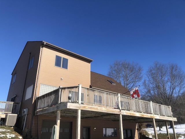 rear view of property featuring a wooden deck and central AC