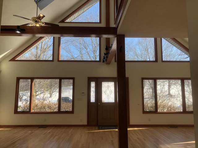 foyer entrance featuring hardwood / wood-style floors, a wealth of natural light, high vaulted ceiling, and ceiling fan