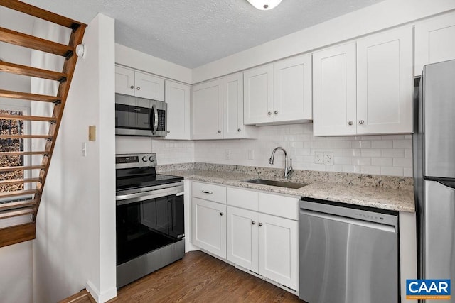 38 Firtree Dr, Wintergreen, VA 22967 - kitchen featuring dark wood finished floors, a sink, white cabinetry, backsplash, and appliances with stainless steel finishes