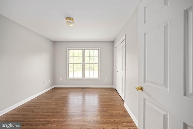  - unfurnished bedroom with wood finished floors, baseboards, and a closet