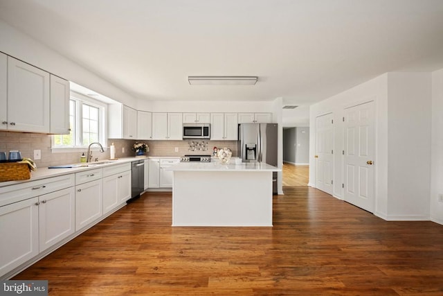  - kitchen with stainless steel appliances, decorative backsplash, a sink, and dark wood finished floors