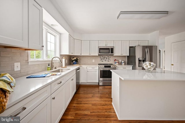  - kitchen featuring appliances with stainless steel finishes, a sink, white cabinetry, and light countertops