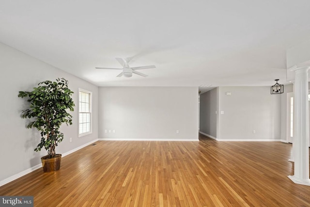  - spare room featuring a ceiling fan, ornate columns, light wood-style flooring, and baseboards