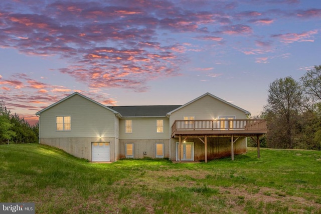  - rear view of property featuring a wooden deck, a lawn, and a garage
