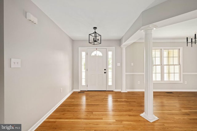  - foyer entrance with light wood-type flooring, ornate columns, baseboards, and a chandelier