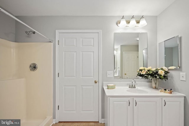  - bathroom with a shower, vanity, and baseboards