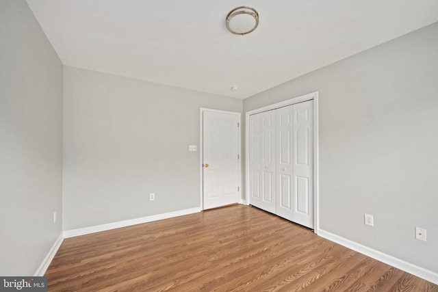  - unfurnished bedroom featuring wood finished floors, baseboards, and a closet