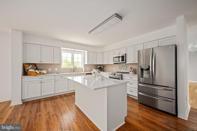  - kitchen featuring appliances with stainless steel finishes, tasteful backsplash, light countertops, and a kitchen island