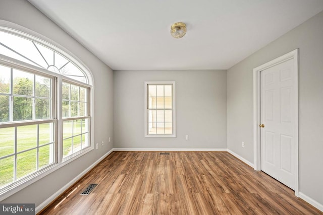  - empty room with plenty of natural light, wood finished floors, and baseboards