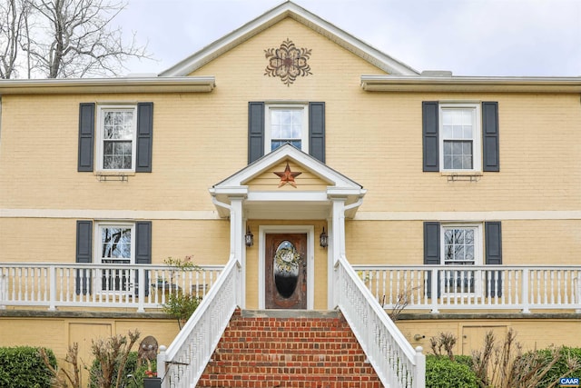 view of front facade with stairway and brick siding
