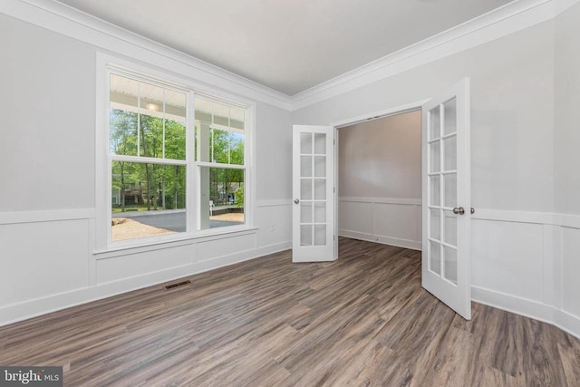 spare room with french doors, ornamental molding, wainscoting, wood finished floors, and a decorative wall