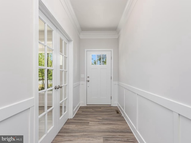 entryway with french doors, ornamental molding, wainscoting, wood finished floors, and a decorative wall