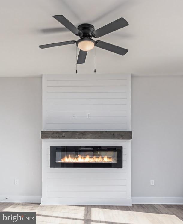 detailed view of a fireplace, wood finished floors, and baseboards