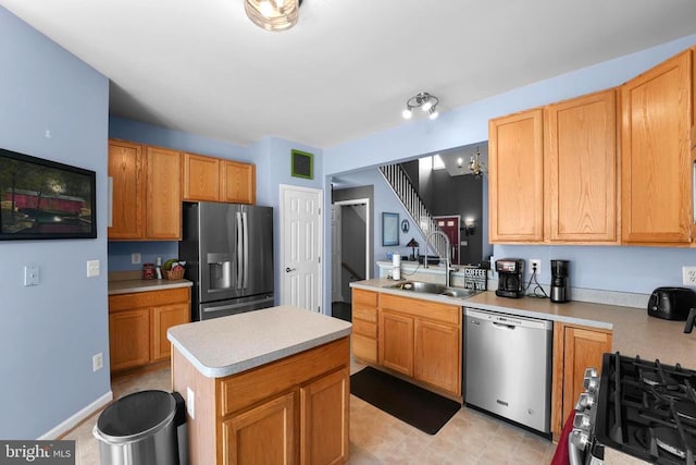kitchen featuring stainless steel appliances, a sink, light countertops, and a center island