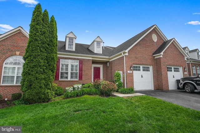 view of front of property with brick siding, a front lawn, asphalt driveway, and a garage