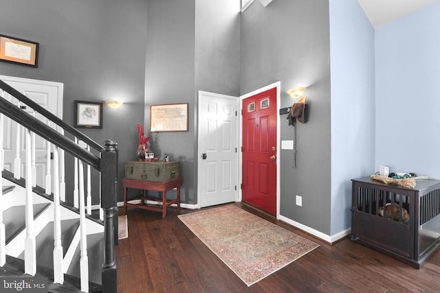foyer entrance with a towering ceiling, baseboards, wood finished floors, and stairway