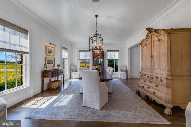 dining room with a chandelier, ornamental molding, and dark wood finished floors