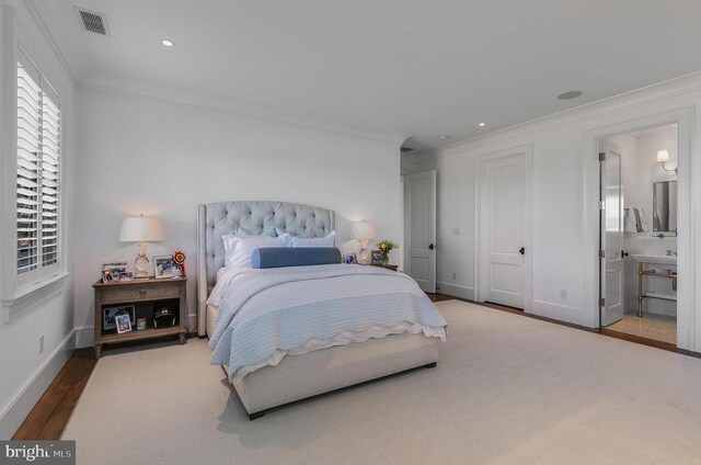 bedroom featuring ornamental molding, baseboards, wood finished floors, ensuite bathroom, and recessed lighting
