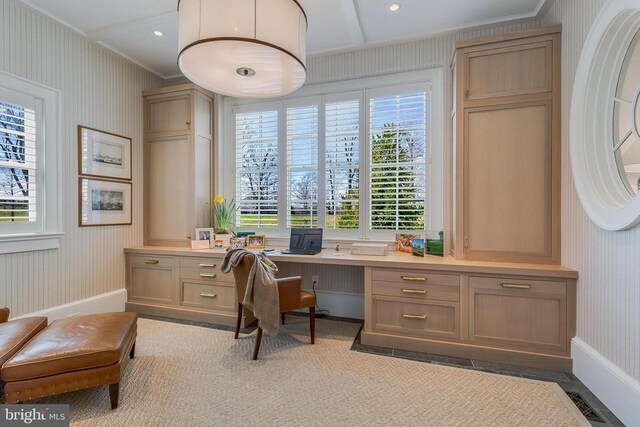 office space featuring wallpapered walls, built in desk, ornamental molding, and baseboards