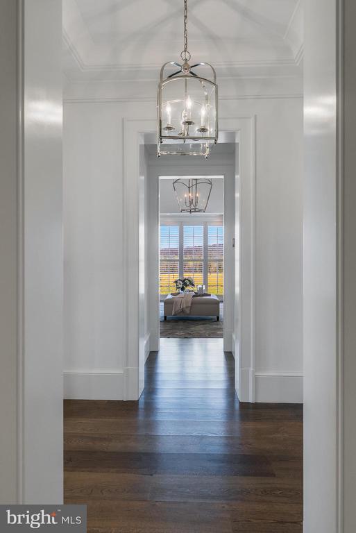 hallway featuring a chandelier, dark wood-style floors, crown molding, and baseboards