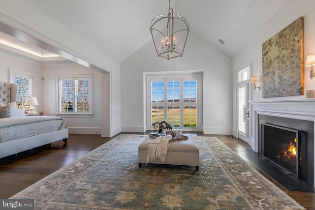 bedroom with a chandelier, wood finished floors, a warm lit fireplace, high vaulted ceiling, and baseboards