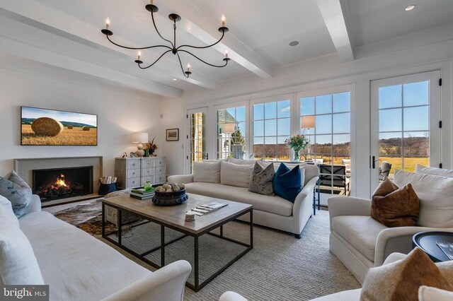living room with beamed ceiling, a chandelier, and a lit fireplace