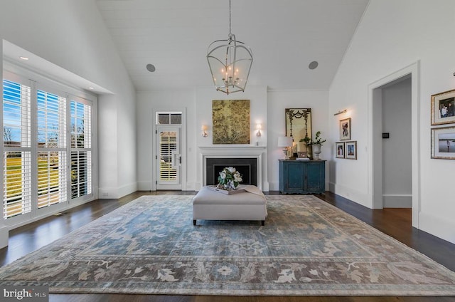 living room featuring a chandelier, wood finished floors, high vaulted ceiling, and baseboards