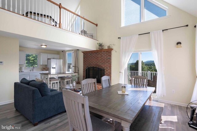 32 Old Hollow Rd, Sperryville, VA 22740 - dining area featuring baseboards, a brick fireplace, a high ceiling, and wood finished floors
