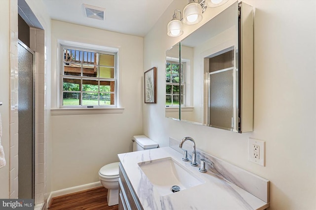  - bathroom featuring healthy amount of natural light, vanity, wood finished floors, and an enclosed shower