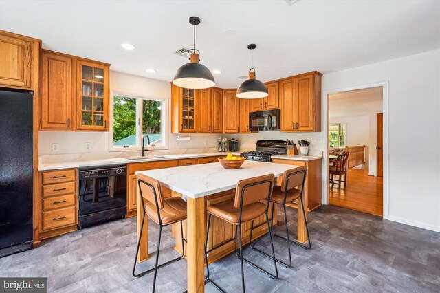  - kitchen featuring black appliances, brown cabinets, healthy amount of natural light, a breakfast bar, and recessed lighting