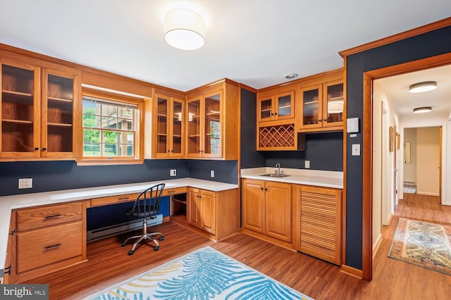  - office with built in study area, a baseboard heating unit, and wood finished floors