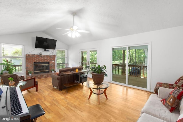 103 Patrick Henry Ct, Locust Grove, VA 22508 - living room featuring lofted ceiling, a textured ceiling, light wood finished floors, a ceiling fan, and a brick fireplace