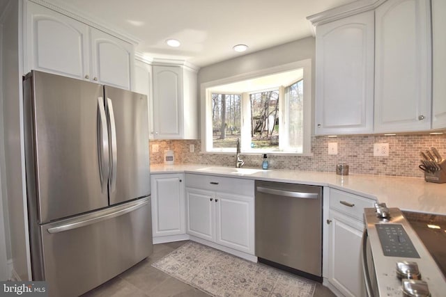  - kitchen with stainless steel appliances, a sink, white cabinets, tasteful backsplash, and recessed lighting