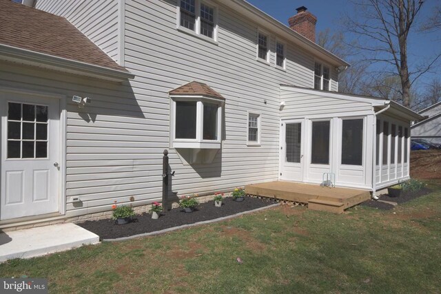  - back of property featuring a chimney, a sunroom, and a yard