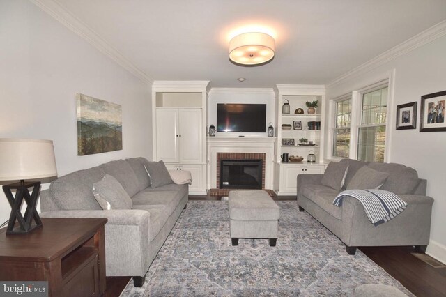  - living area with crown molding, a brick fireplace, dark wood-type flooring, built in features, and baseboards
