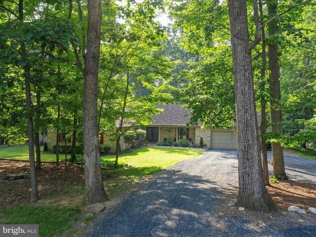  - obstructed view of property with gravel driveway, a front lawn, and a garage