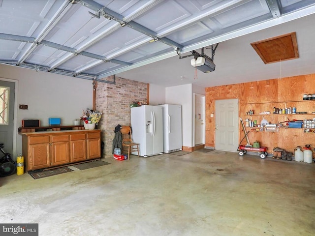  - garage featuring white refrigerator with ice dispenser, freestanding refrigerator, a garage door opener, and wood walls