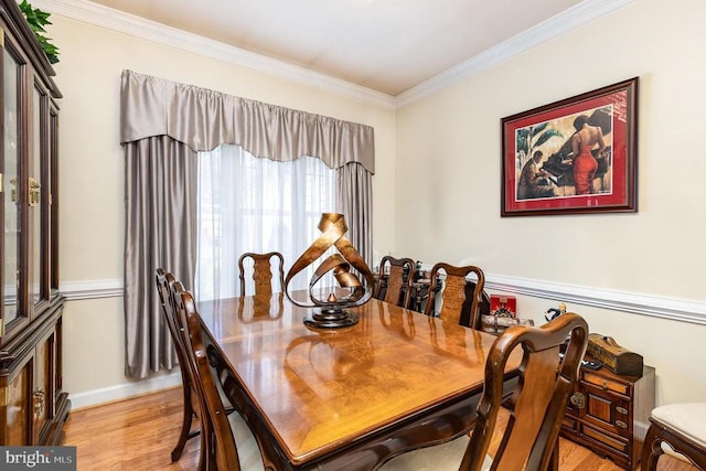 dining space featuring light wood-style flooring, ornamental molding, and baseboards