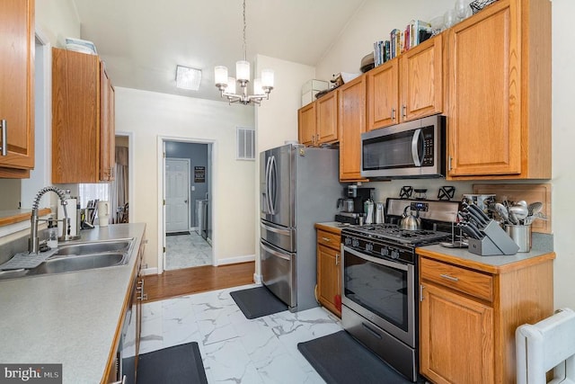 kitchen featuring appliances with stainless steel finishes, a sink, light marble finish flooring, a chandelier, and light countertops