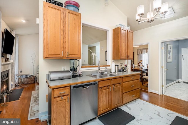 kitchen featuring dishwasher, a sink, a chandelier, a fireplace with flush hearth, and light countertops