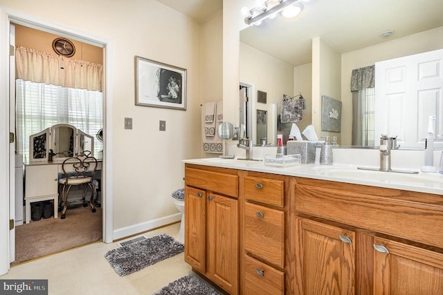 bathroom with double vanity, toilet, and baseboards