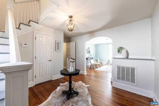 foyer entrance with baseboards, dark wood-style flooring, an inviting chandelier, visible vents, and arched walkways