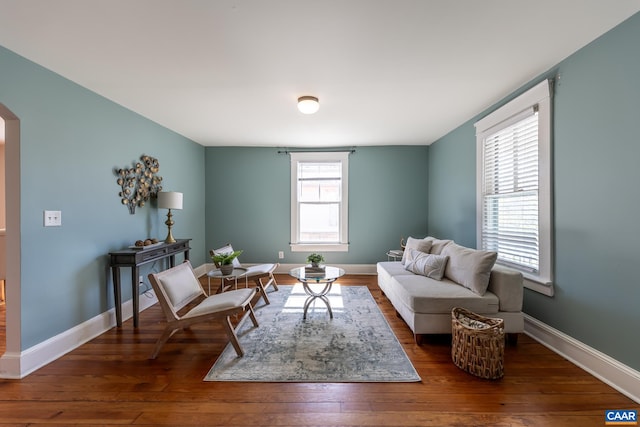 living room with wood-type flooring, arched walkways, and baseboards