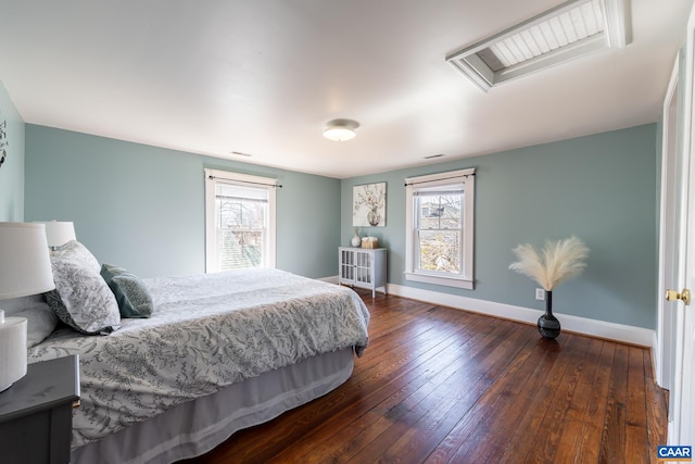 bedroom with multiple windows, visible vents, baseboards, and hardwood / wood-style flooring